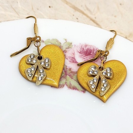 Boucles d’oreilles Gloria – pendants cœurs dorés en pâte polymère avec nœud strass brillant